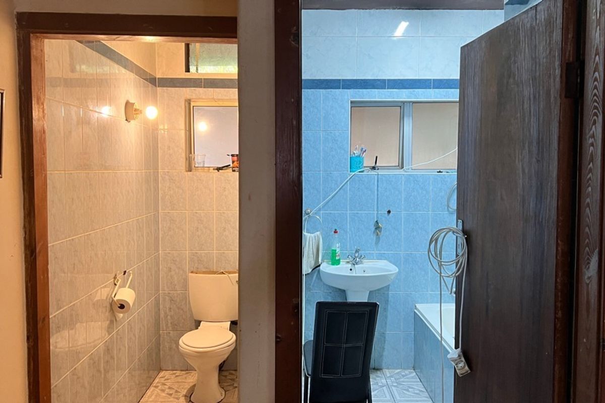 A functional bathroom featuring a pedestal basin, toilet, and bathtub with blue wall tiling and tiled flooring.