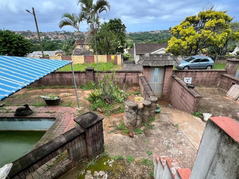 Outdoor pool area featuring a swimming pool, concrete paving, and brick boundary walls, requiring significant maintenance and restoration.