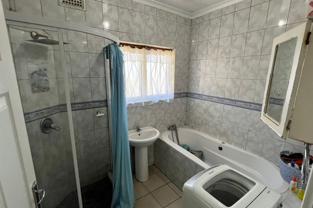 A functional bathroom featuring a shower enclosure, pedestal basin, and bathtub with full-height wall tiling and tiled flooring.