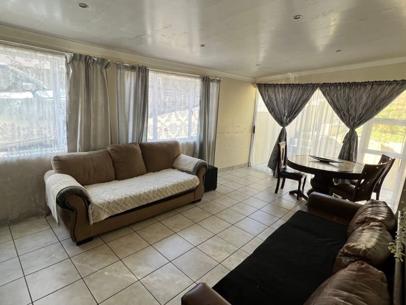 Open-plan living and dining area featuring tiled flooring, recessed lighting, and large windows with sliding door access to the exterior.