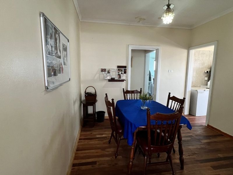 Dining room featuring hardwood flooring and ceiling light fixture, with visible water staining on the ceiling requiring attention.