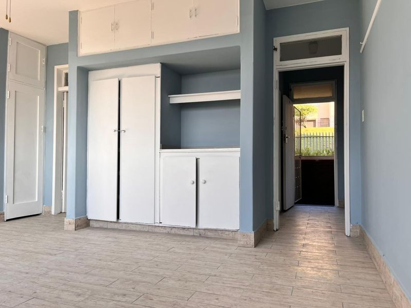 An empty living area featuring built-in storage cabinetry, tiled flooring, and a doorway leading to an exterior space.