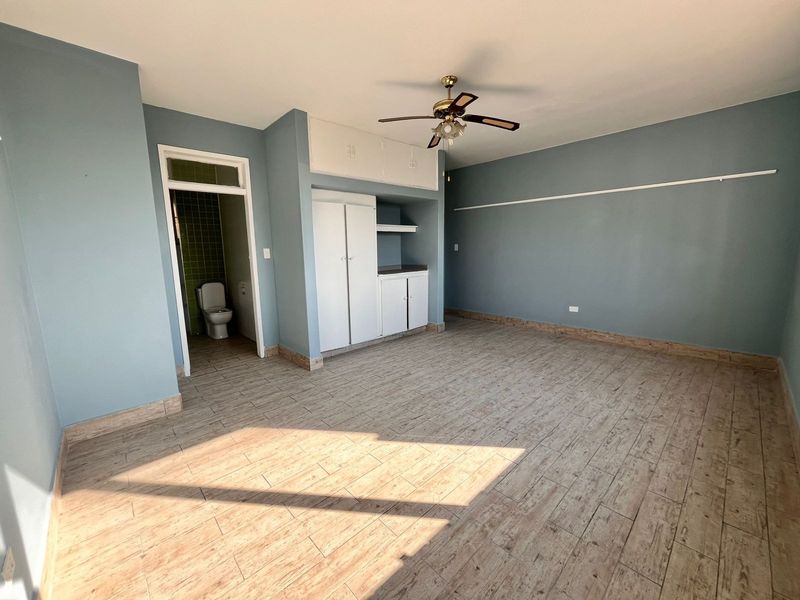Spacious bedroom featuring wood-look tiled flooring, built-in storage cupboards, a ceiling fan, and direct access to an en-suite bathroom.