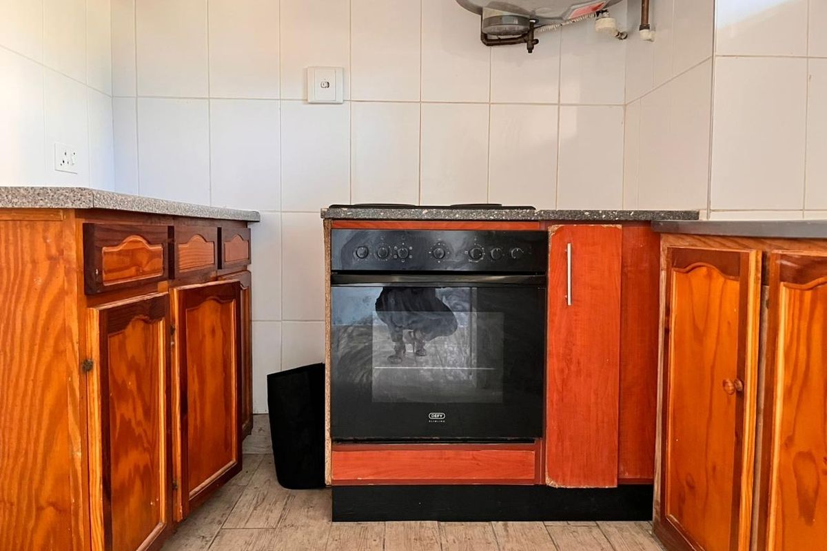 A dated kitchen featuring wooden cabinetry, a built-in oven, and tiled splashbacks, offering potential for a modern renovation.