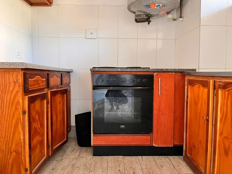 A dated kitchen featuring wooden cabinetry, a built-in oven, and tiled splashbacks, offering potential for a modern renovation.