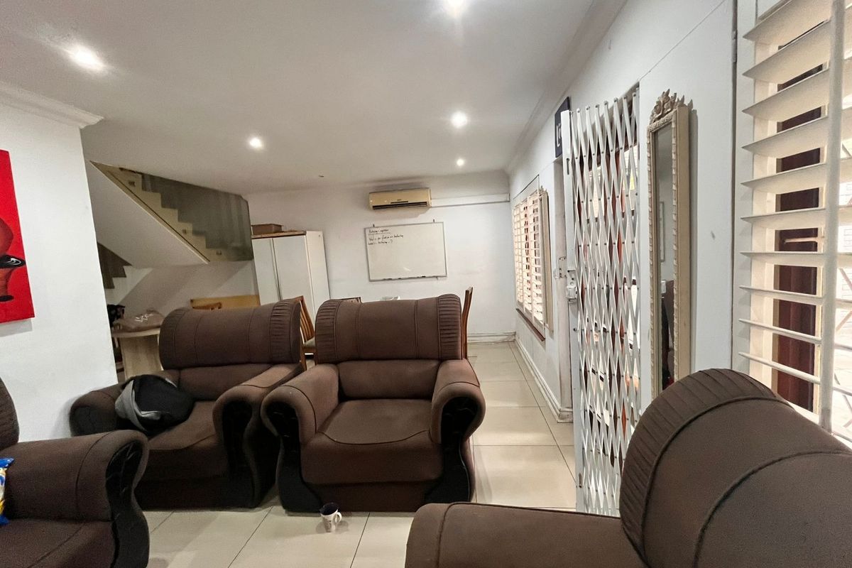 Open-plan living area featuring tiled flooring, recessed downlights, a split-system air conditioner, and a staircase leading to the upper level.