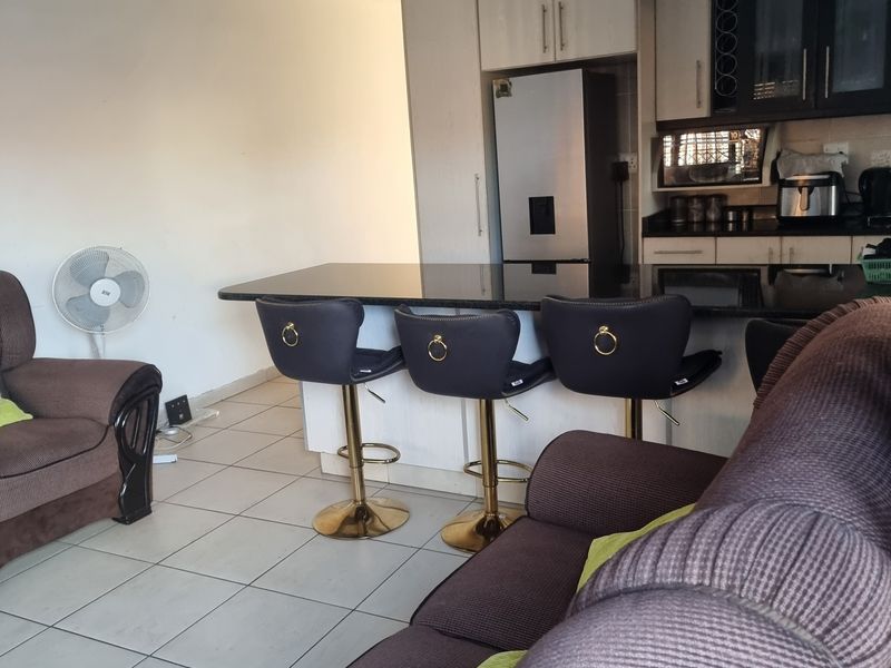 Open plan living area featuring a kitchen with granite island and built-in cabinetry, seamlessly connected to the lounge space with tiled flooring throughout.