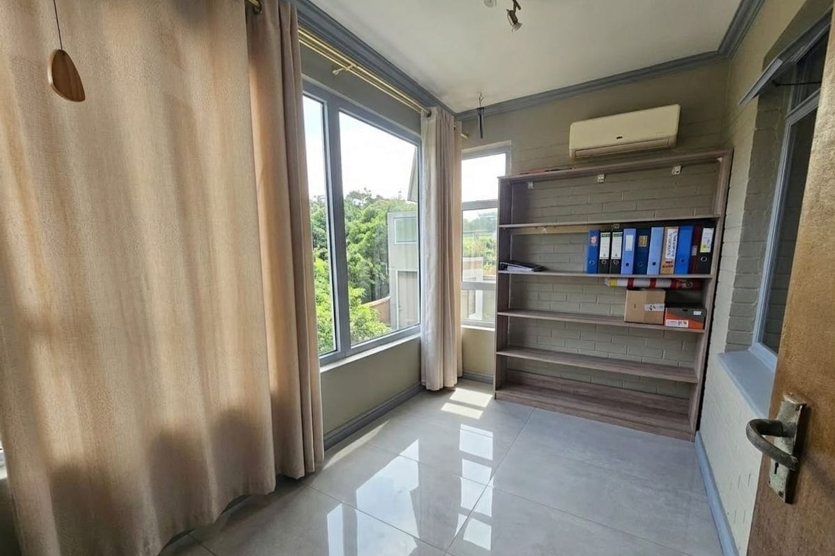 A bedroom featuring tiled flooring, large windows with natural light, and a wall-mounted air conditioning unit.