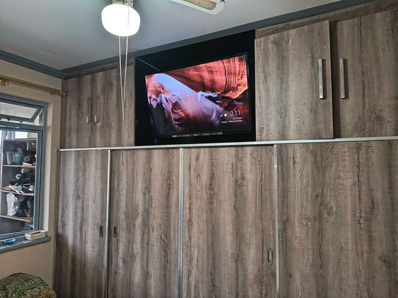 Bedroom featuring extensive floor-to-ceiling built-in wooden cabinetry with integrated television storage and sliding doors.