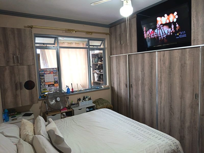 A bedroom featuring extensive built-in wooden cabinetry and a ceiling fan, providing ample storage space and functional lighting.