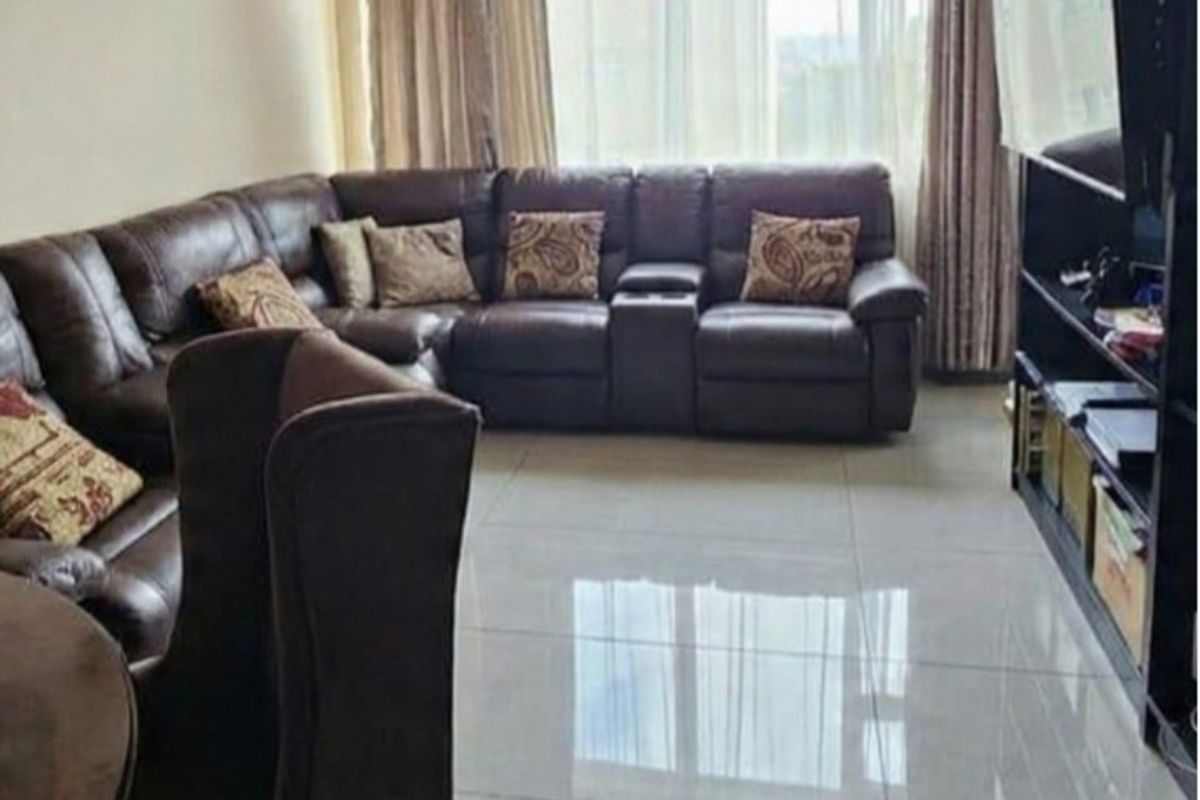A spacious living room featuring large format floor tiles and a large window allowing for natural light.