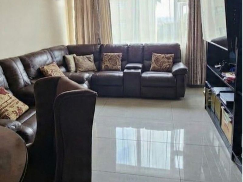 A spacious living room featuring large format floor tiles and a large window allowing for natural light.