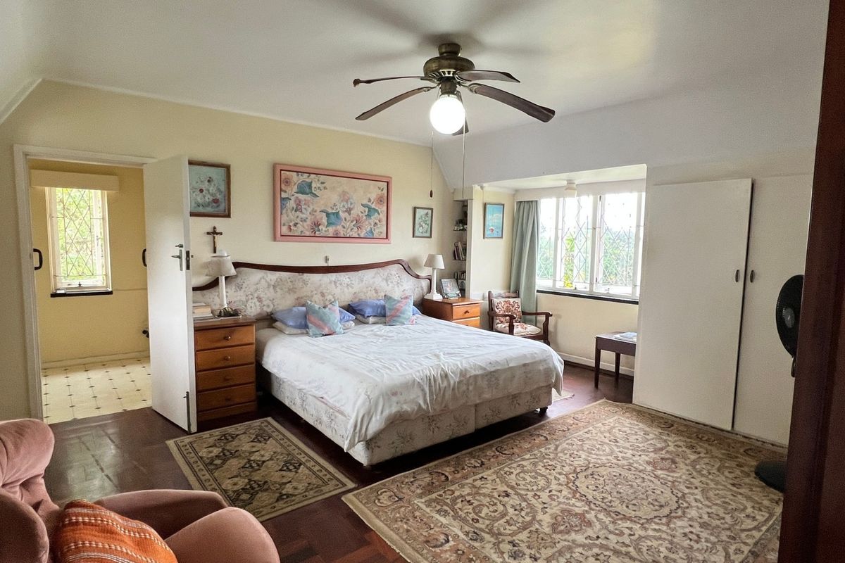 Spacious bedroom featuring parquet flooring, built-in cupboards, and classic leaded glass windows, offering a comfortable and well-lit living space.