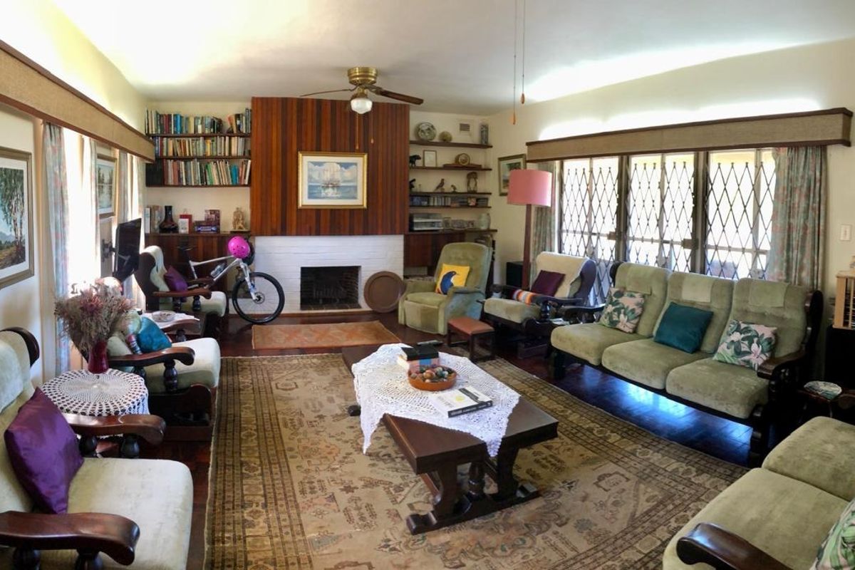 Spacious living room featuring a central fireplace with wood paneling, built-in shelving, and large windows with security gates.