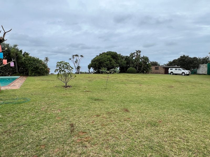 Spacious garden area featuring a swimming pool with paved surround and a detached outbuilding set within a large lawn.