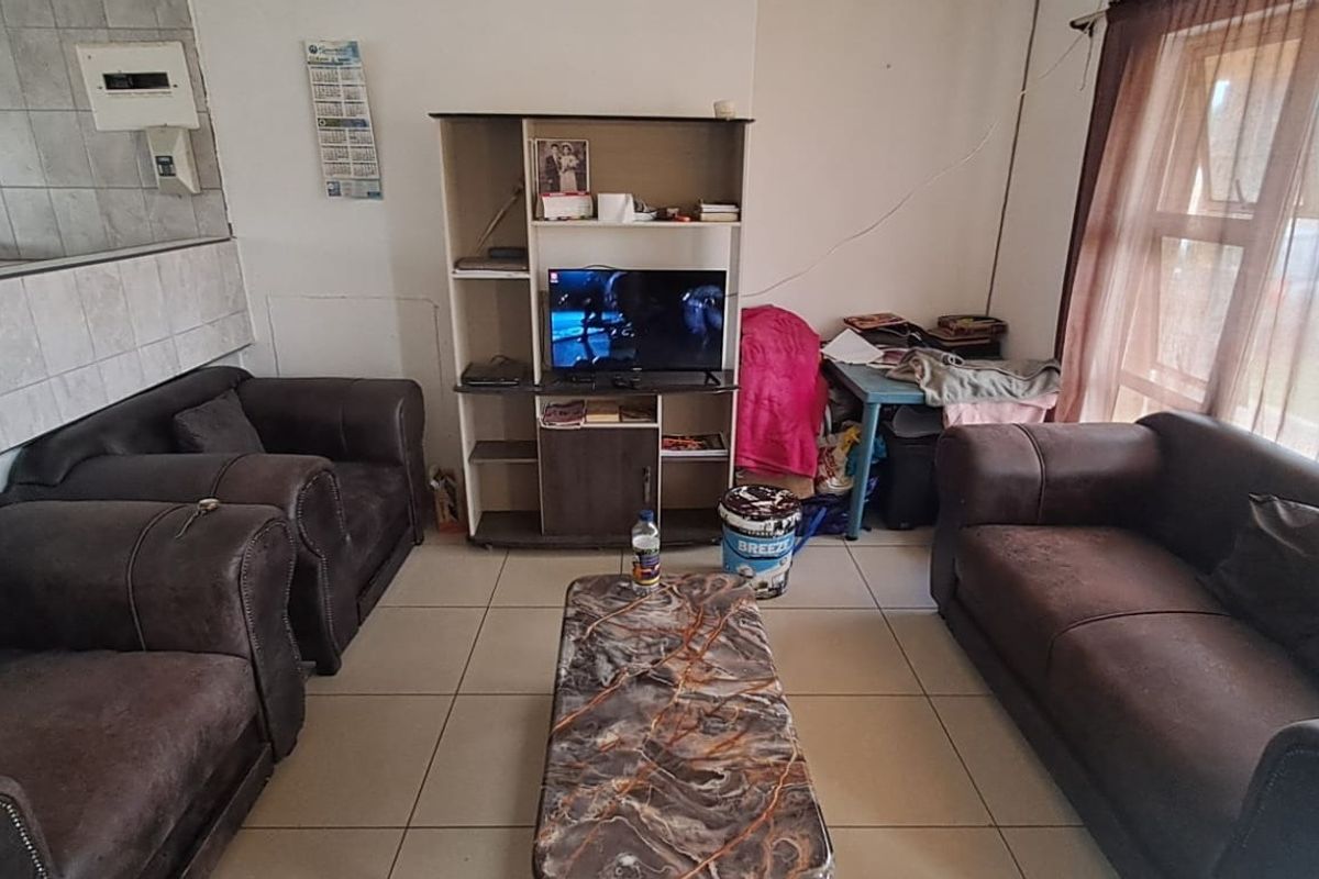 A living room area featuring tiled flooring and a sliding glass door, providing access to the exterior.