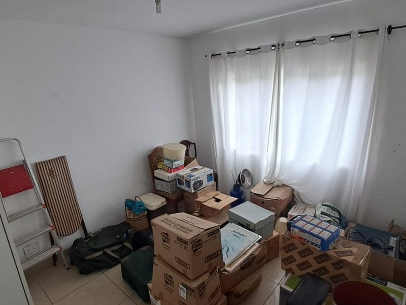 A bedroom featuring tiled flooring and a built-in cupboard, currently used for storage. The space requires cosmetic updates to improve its overall condition.