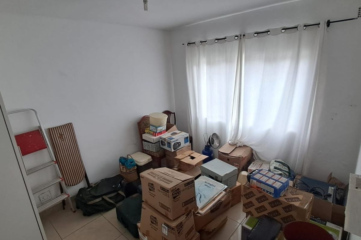 A bedroom featuring tiled flooring and a built-in cupboard, currently used for storage. The space requires cosmetic updates to improve its overall condition.