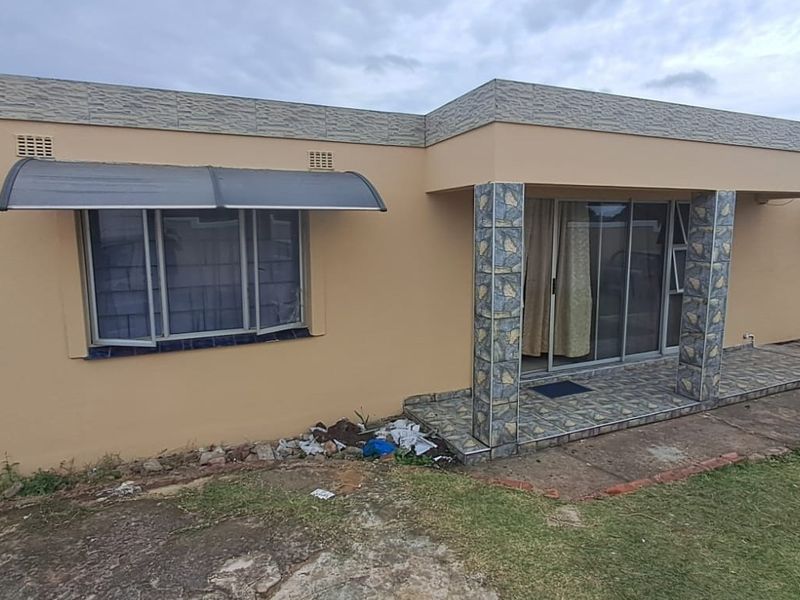 Rear exterior view of the house featuring a tiled patio area, sliding glass doors, and decorative tiled support columns.