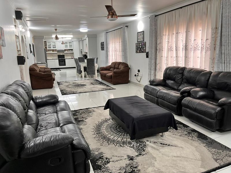 Spacious open-plan living and dining area featuring tiled floors, ceiling fans, and a modern kitchen with built-in cabinetry and appliances.