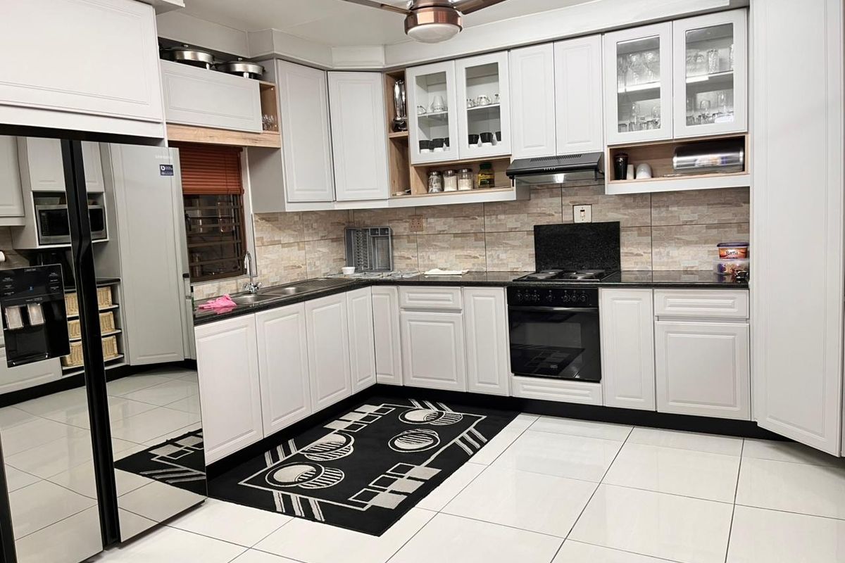 A well-maintained kitchen featuring white cabinetry, granite countertops, integrated appliances, and a tiled backsplash, offering a clean and functional cooking space.