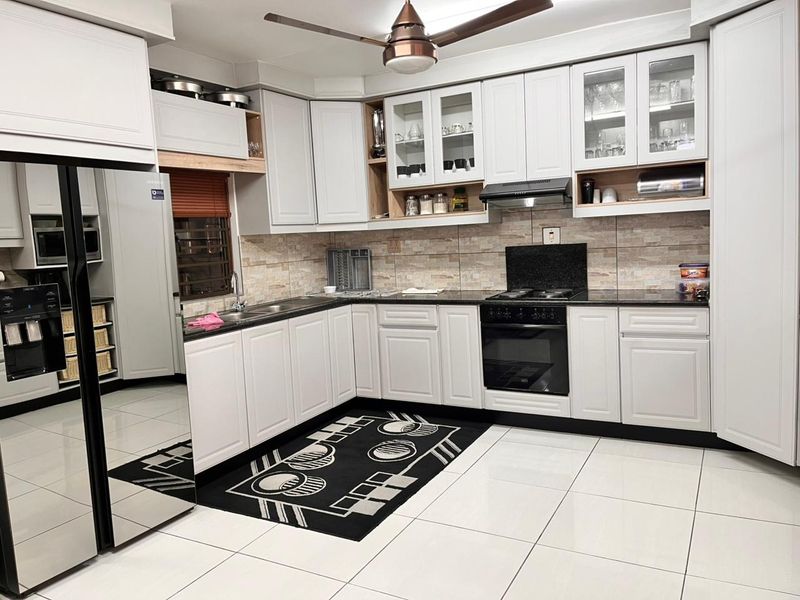 A well-maintained kitchen featuring white cabinetry, granite countertops, integrated appliances, and a tiled backsplash, offering a clean and functional cooking space.
