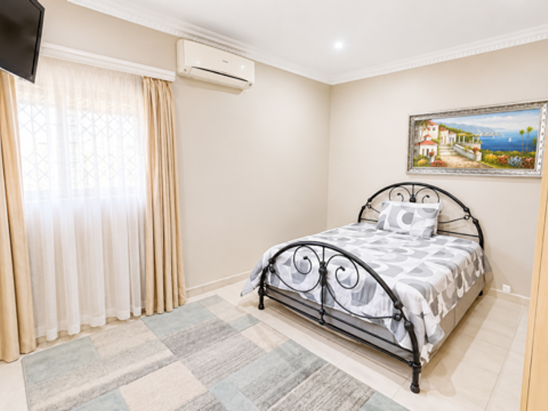 A well-maintained bedroom featuring tiled flooring, built-in cabinetry, and a wall-mounted air conditioning unit.