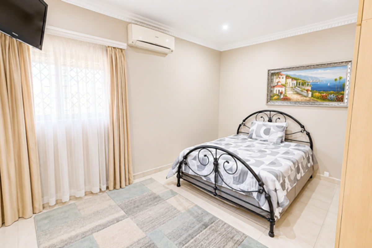 A well-maintained bedroom featuring tiled flooring, built-in cabinetry, and a wall-mounted air conditioning unit.