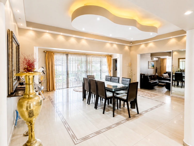Spacious open-plan dining area featuring a decorative bulkhead ceiling with recessed lighting, polished tiled floors, and large sliding doors leading to the exterior.