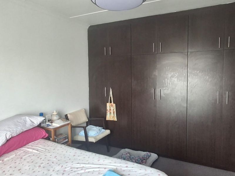 A bedroom featuring dark wood built-in cupboards providing ample storage space.