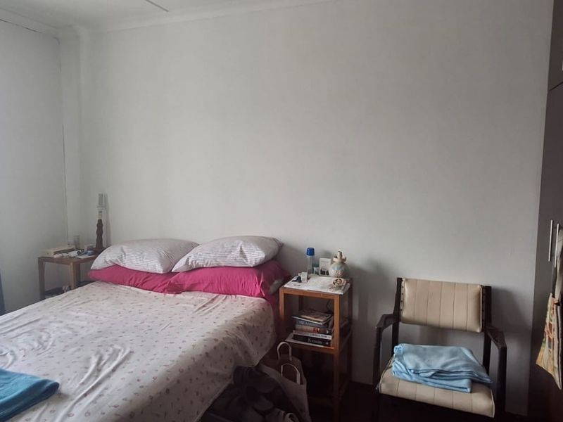 A functional bedroom featuring built-in cupboards and a window with natural light, providing a comfortable and practical living space.