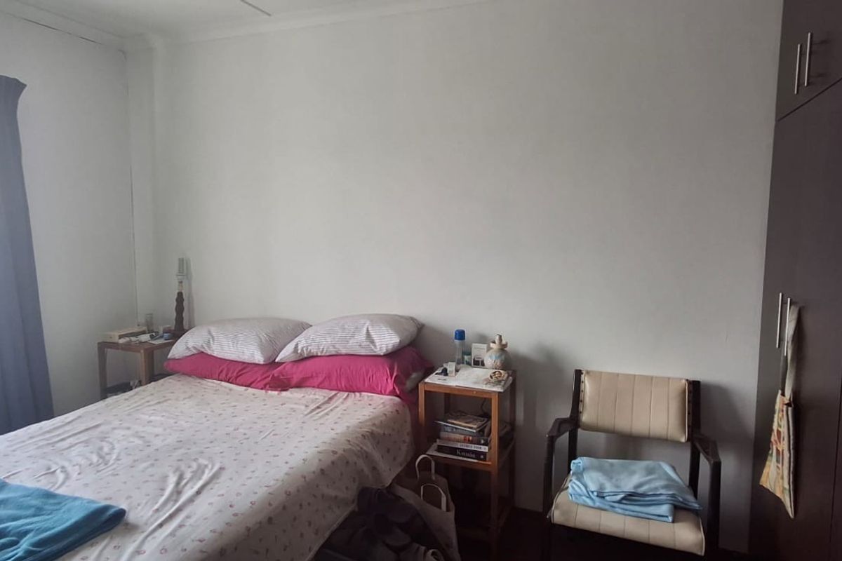 A functional bedroom featuring built-in cupboards and a window with natural light, providing a comfortable and practical living space.