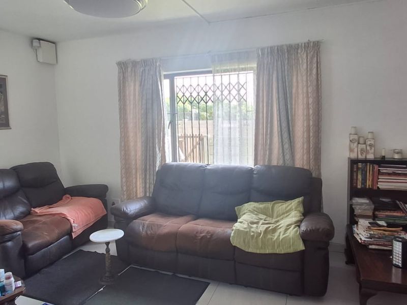 A living room featuring tiled flooring and a window fitted with a security gate, providing a functional and secure living space.