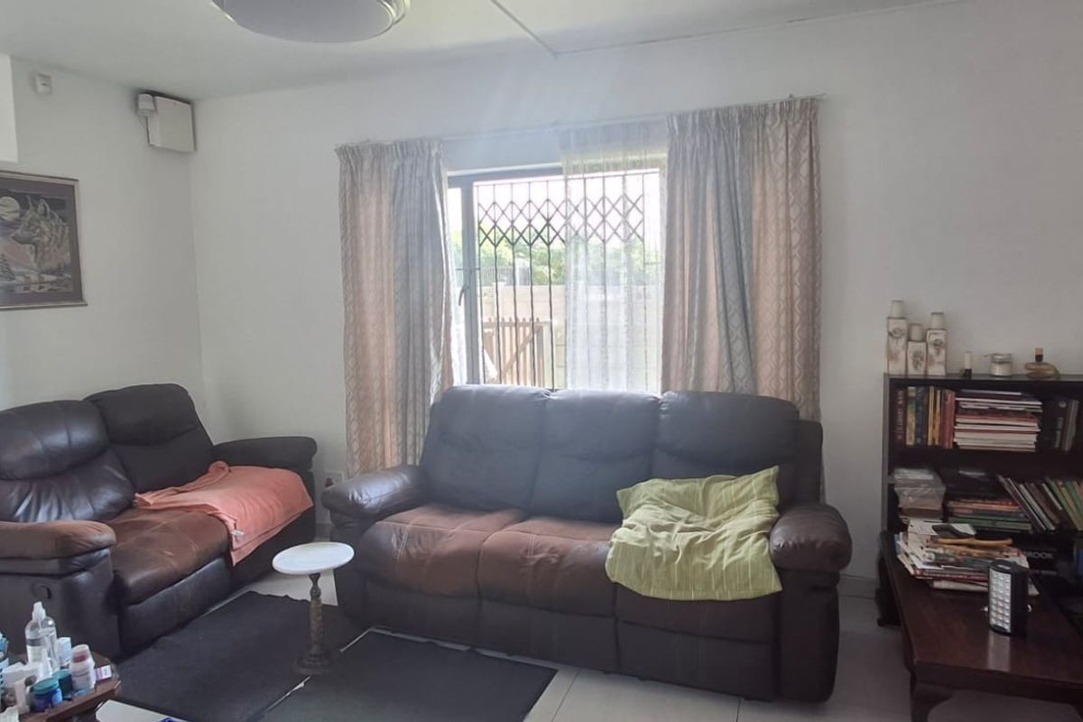 A living room featuring tiled flooring and a window fitted with a security gate, providing a functional and secure living space.