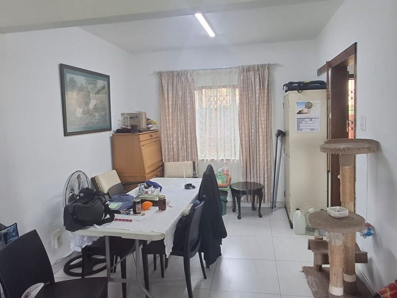 A functional dining area featuring tiled flooring and a window with security bars, providing a practical space for meals.