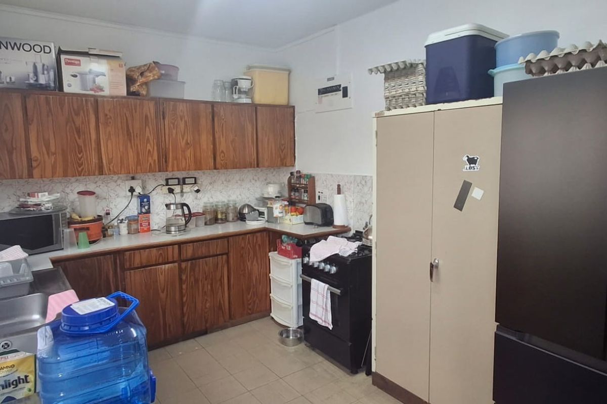 A functional kitchen featuring wood-look cabinetry, tiled backsplash, and tiled flooring, offering a dated aesthetic with potential for modern renovation.