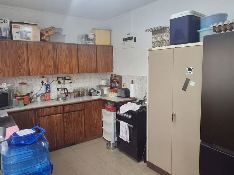 A functional kitchen featuring wood-look cabinetry, tiled backsplash, and tiled flooring, offering a dated aesthetic with potential for modern renovation.