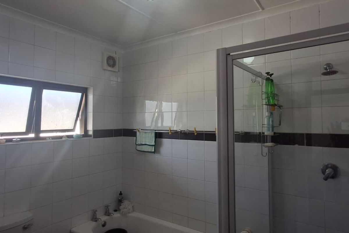 A functional bathroom featuring a shower enclosure, bathtub, and tiled walls with a neutral design, providing a practical space for daily use.