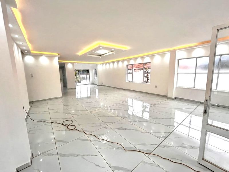 Spacious open-plan living area featuring high-gloss marble-look porcelain floor tiles, modern recessed ceiling lighting, and cove accent lighting throughout.