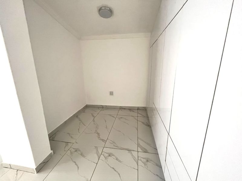 A clean, modern hallway featuring high-gloss built-in cabinetry and large-format marble-look floor tiles.