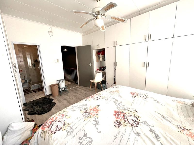 Bedroom featuring extensive built-in cupboards, a ceiling fan, laminate flooring, and direct access to an en-suite bathroom.