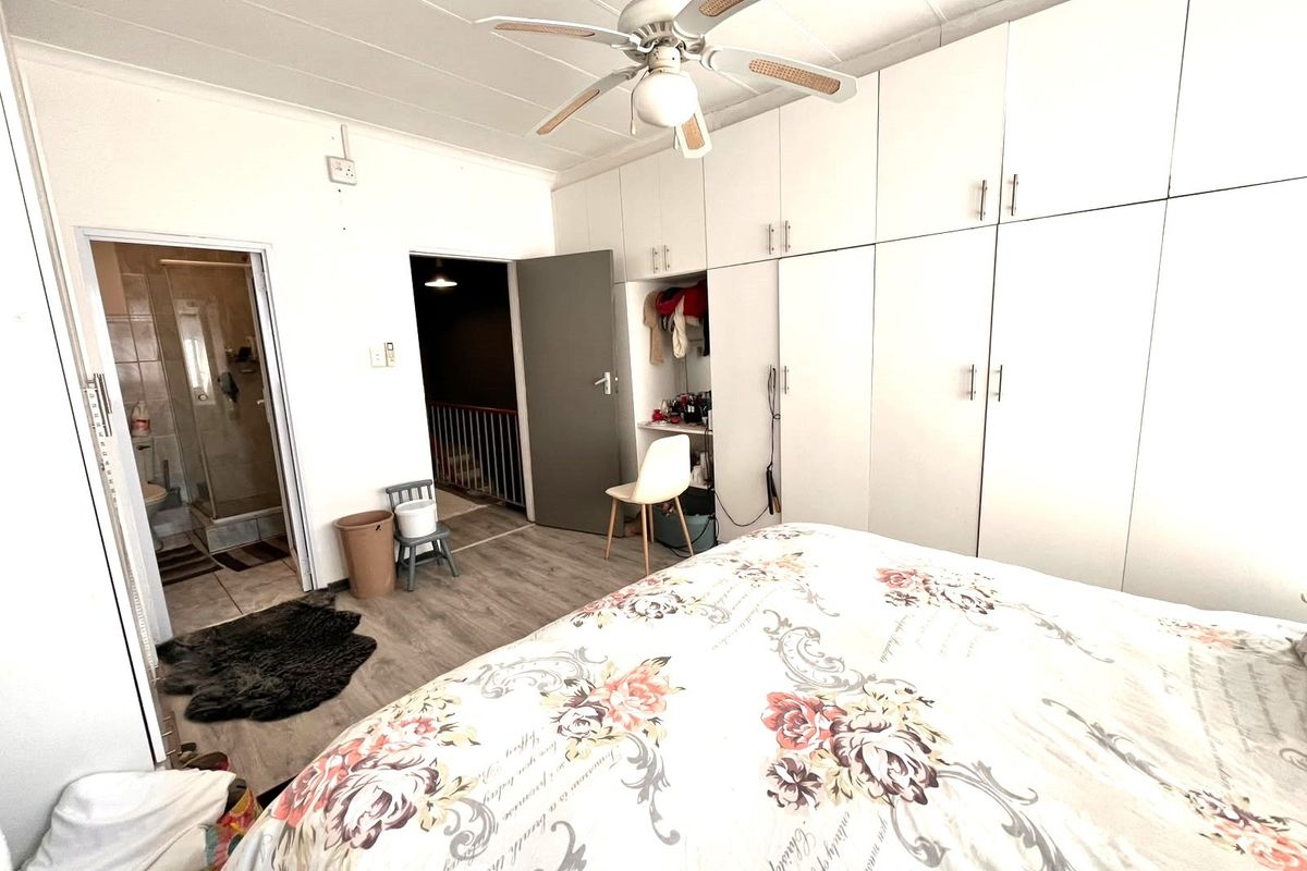 Bedroom featuring extensive built-in cupboards, a ceiling fan, laminate flooring, and direct access to an en-suite bathroom.