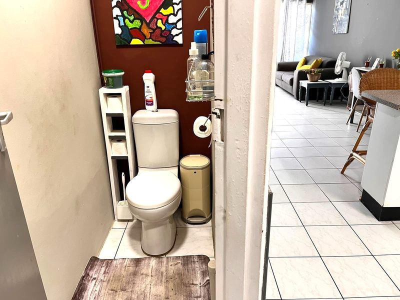 A compact guest toilet featuring tiled flooring and a standard white toilet suite, conveniently located adjacent to the main living area.