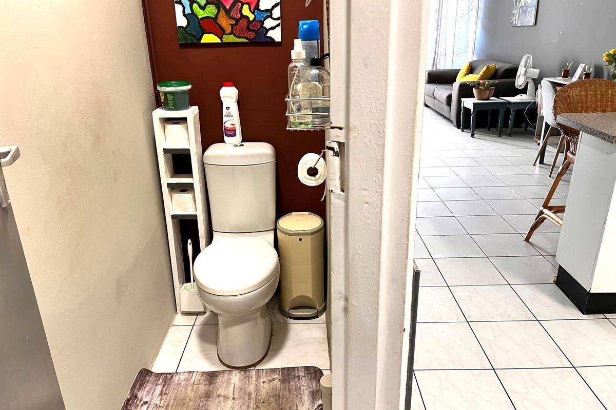 A compact guest toilet featuring tiled flooring and a standard white toilet suite, conveniently located adjacent to the main living area.