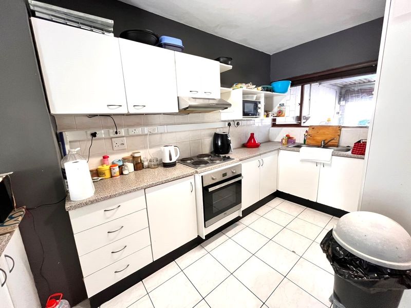 A functional kitchen featuring white cabinetry, laminate countertops, built-in oven and hob, and tiled flooring with a tiled backsplash.