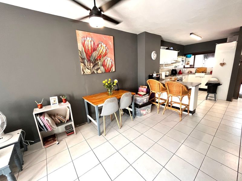 Open plan living and kitchen area featuring tiled flooring, a breakfast bar, and a ceiling fan, creating a functional and connected living space.