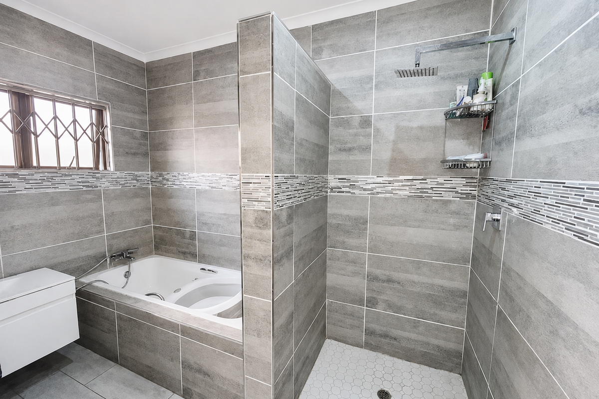 Modern bathroom featuring a built-in bathtub and a separate walk-in shower with grey tiled walls and a mosaic accent border.
