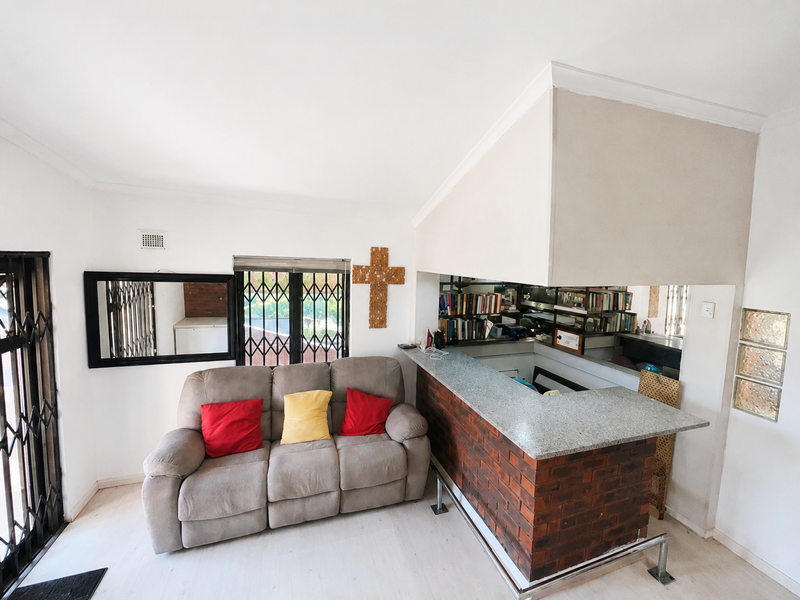 Open plan living area featuring a brick breakfast bar with granite countertop and secure metal gate access.