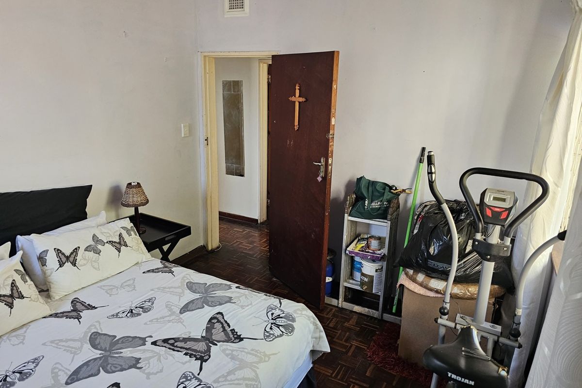 A bedroom featuring traditional parquet flooring and a standard door, requiring cosmetic updates to improve the overall aesthetic and condition of the space.