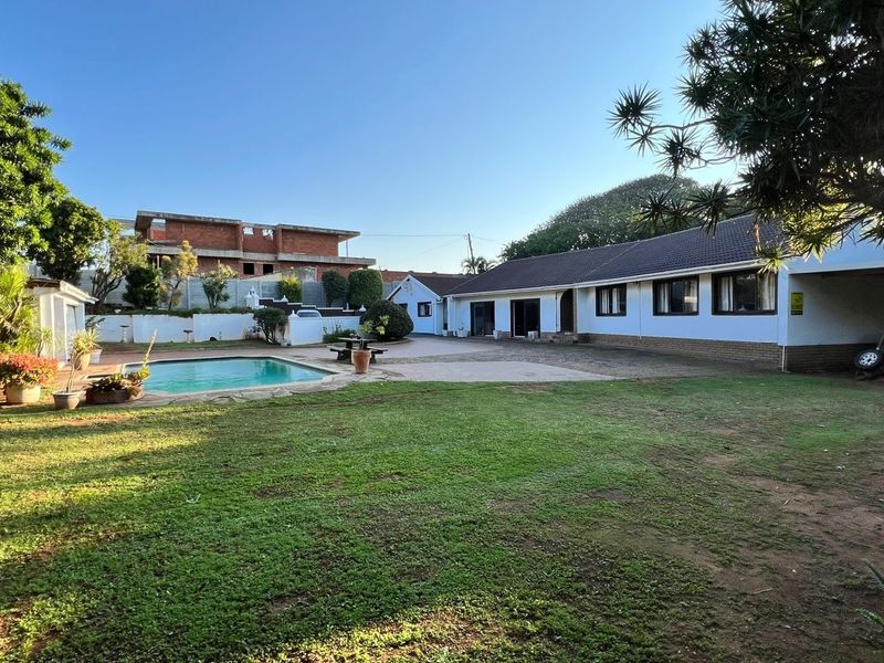 Spacious rear garden featuring a swimming pool, paved patio area, and a single-story dwelling with a tiled roof.